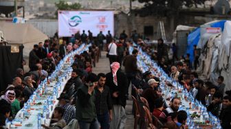 Pengungsi Suriah berbagi makanan berbuka puasa bersama saat bulan suci Ramadhan di Kota Al-Bab, provinsi Aleppo, Suriah, Kamis (7/4/2022). [Bakr ALKASEM / AFP]