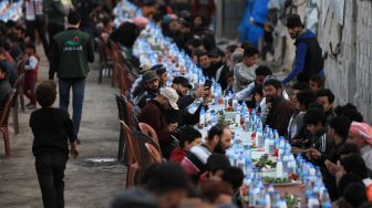 Pengungsi Suriah berbagi makanan berbuka puasa bersama saat bulan suci Ramadhan di Kota Al-Bab, provinsi Aleppo, Suriah, Kamis (7/4/2022). [Bakr ALKASEM / AFP]
