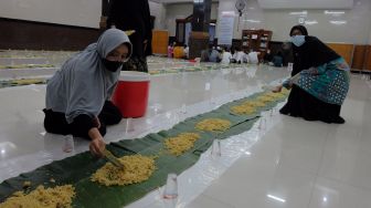 Sejumlah warga Muslimat menyiapkan makanan di atas lembaran daun pisang untuk makan bersama atau megibung saat waktu berbuka puasa di Masjid Baitul Makmur, Denpasar, Bali, Jumat (8/4/2022). [ANTARA FOTO/Nyoman Hendra Wibowo/wsj]
