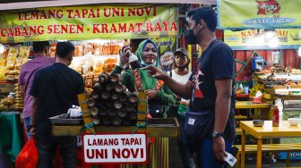 Warga membeli Lemang untuk berbuka puasa di Sentra kuliner Nasi Kapau di Jalan Kramat Raya, Senen, Jakarta Pusat, Selasa (12/4/2021). [Suara.com/Alfian Winanto]