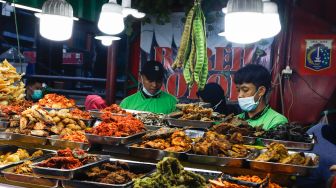 Pelayan mengambil menu makanan di Sentra kuliner Nasi Kapau di Jalan Kramat Raya, Senen, Jakarta Pusat, Selasa (12/4/2021). [Suara.com/Alfian Winanto]