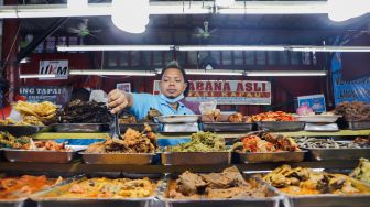 Pelayan mengambil menu makanan di Sentra kuliner Nasi Kapau di Jalan Kramat Raya, Senen, Jakarta Pusat, Selasa (12/4/2021). [Suara.com/Alfian Winanto]