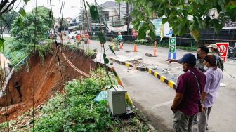 Warga melihat lokasi longsor didaerah bantaran sungai Ciliwung, Pengadegan Timur, Pancoran, Jakarta Selatan, Selasa (12/4/2022). [Suara.com/Alfian Winanto]