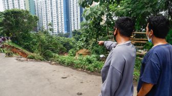 Warga melihat lokasi longsor didaerah bantaran sungai Ciliwung, Pengadegan Timur, Pancoran, Jakarta Selatan, Selasa (12/4/2022). [Suara.com/Alfian Winanto]