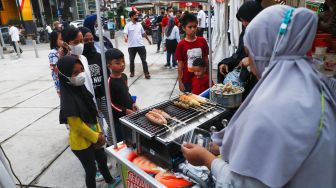 Pengunjung membeli makanan di acara Festival Kuliner Nusantara di Taman Ismail Marzuki (TIM), Cikini, Jakarta Pusat, Rabu (13/4/2022). [Suara.com/Alfian Winanto]