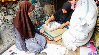 Pengrajin menyablon nama pada sajadah di Kawasan Kebon Melati, Tanah Abang, Jakarta Pusat, Kamis (14/4/2022). [Suara.com/Alfian Winanto]