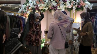 Pengunjung memilih busana muslim di area bazaar pakaian saat gelaran Indonesia Fashion Week 2022, Jakarta Convention Center (JCC), Jakarta, Jumat (15/4/2022). [Suara.com/Angga Budhiyanto]