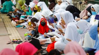 Umat Islam membaca Al-Quran sambil menunggu waktu berbuka puasa di halaman Masjid Raya Jakarta Islamic Center, Jakarta Utara, Senin (18/4/2022). [Suara.com/Alfian Winanto]