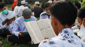 Umat Islam membaca Al-Quran sambil menunggu waktu berbuka puasa di halaman Masjid Raya Jakarta Islamic Center, Jakarta Utara, Senin (18/4/2022). [Suara.com/Alfian Winanto]