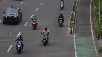 Sejumlah kendaraan melintas di samping jalur khusus sepeda di Jalan Jenderal Sudirman, Jakarta, Senin (18/4/2022). [Suara.com/Angga Budhiyanto]