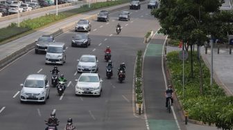 Pesepeda melintasi jalur khusus sepeda di Jalan Jenderal Sudirman, Jakarta, Senin (18/4/2022). [Suara.com/Angga Budhiyanto]