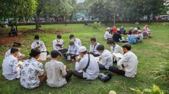 Umat Islam membaca Al-Quran sambil menunggu waktu berbuka puasa di halaman Masjid Raya Jakarta Islamic Center, Jakarta Utara, Senin (18/4/2022). [Suara.com/Alfian Winanto]