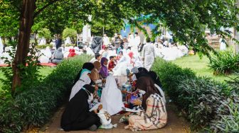 Umat Islam membaca Al-Quran sambil menunggu waktu berbuka puasa di halaman Masjid Raya Jakarta Islamic Center, Jakarta Utara, Senin (18/4/2022). [Suara.com/Alfian Winanto]