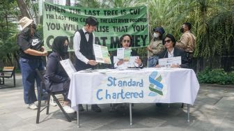 Sejumlah aktivis melakukan aksi teatrikal fine dining restaurant di depan kantor Standard Chartered di kawasan Setiabudi, Jakarta Selatan, Selasa (19/4/2022). [Suara.com/Alfian Winanto]