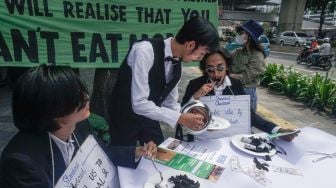 Sejumlah aktivis melakukan aksi teatrikal fine dining restaurant di depan kantor Standard Chartered di kawasan Setiabudi, Jakarta Selatan, Selasa (19/4/2022). [Suara.com/Alfian Winanto]