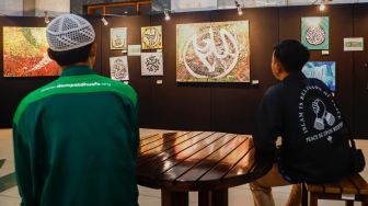 Pengunjung melihat Pameran Kaligrafi Kontemporer Internasional di Masjid Raya Jakarta Islamic Center, Jakarta Utara, Senin (18/4/2022). [Suara.com/Alfian Winanto]