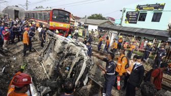 Sejumlah petugas melakukan evakuasi mobil yang tertabrak KRL di kawasan Rawageni, Cipayung, Depok, Jawa Barat, Rabu (20/4/2022).  ANTARA FOTO/Asprilla Dwi Adha