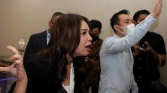 Penyanyi Sri Rossa Roslaina Handiyani atau Rossa menjawab pertanyaan dari awak media usai menjalani pemeriksaan di Bareskrim Polri, Jakarta, Kamis (21/4/2022) malam. [Suara.com/Angga Budhiyanto]