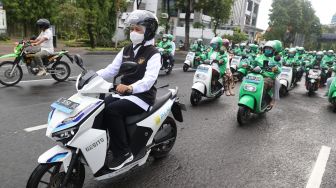 Gubernur Jawa Timur Khofifah Indar Parawansa (kiri) mengendarai motor listrik GESITS saat mengikuti konvoi bersama 100 pengemudi ojek daring perempuan di Surabaya, Jawa Timur, Kamis (21/4/2022). ANTARA FOTO/Trisnadi