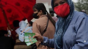 Warga menunjukkan tiket mudik gratis angkutan Lebaran di Polda Metro Jaya, Jakarta, Sabtu (23/4/2022). [Suara.com/Angga Budhiyanto]