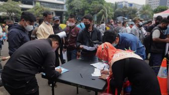 Warga mengisi formulir untuk mendaftar mudik gratis angkutan Lebaran di Polda Metro Jaya, Jakarta, Sabtu (23/4/2022). [Suara.com/Angga Budhiyanto]