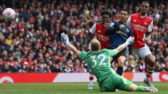 Striker Manchester United Cristiano Ronaldo (kedua dari kanan) menembak bola melewati kiper Arsenal Aaron Ramsdale untuk mencetak gol saat pertandingan sepak bola Liga Premier Inggris antara Arsenal dan Manchester United di Stadion Emirates, London, Inggris, Sabtu (23/4/2022). [Glyn KIRK/AFP]
