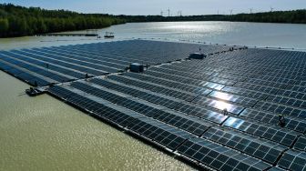 Pemandangan udara menunjukkan para pekerja merakit panel surya di pembangkit fotovoltaik terapung di danau Silbersee, Haltern, Jerman, Jumat (22/4/2022). [Ina FASSBENDER / AFP]