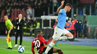 Bek AC Milan Pierre Kalulu (kiri) berebut bola dengan gelandang Lazio Sergej saat pertandingan sepak bola Serie A Liga Italia antara Lazio dan AC Milan di Stadion Olimpiade, Roma, Italia, Minggu (24/4/2022). [VINCENZO PINTO / AFP]