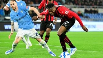 Penyerang AC Milan Rafael Leão (kanan) berebut bola dengan gelandang Lazio Manuel Lazzari saat pertandingan sepak bola Serie A Liga Italia antara Lazio dan AC Milan di Stadion Olimpiade, Roma, Italia, Minggu (24/4/2022). [VINCENZO PINTO / AFP]