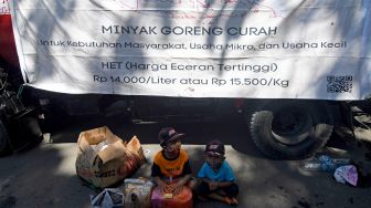 Dua orang anak duduk di dekat tanki minyak goreng curah saat proses pendistribusian pada gelaran pasar murah di halaman Korem 132 Tadulako di Palu, Sulawesi Tengah, Selasa (26/4/2022). ANTARA FOTO/Mohamad Hamzah