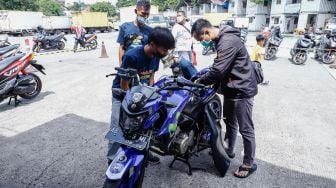 Petugas mengecek keadaan sepeda motor sebelum dikemas dan dikirim menggunakan kereta di Stasiun Kampung Bandan, Jakarta Utara, Selasa (26/4/2022). [Suara.com/Alfian Winanto]