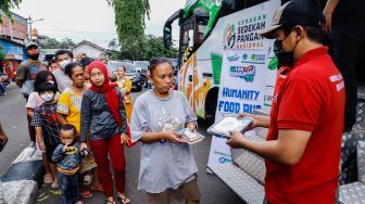 Petugas membagikan bantuan makanan kepada warga didepan Humanity Food Bus di Cipete Utara, Jakarta Selatan, Jumat (29/4/2022). [Suara.com/Alfian Winanto]