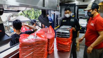 Petugas menyiapkan makanan di dalam ACT Humanity Food Bus di Cipete Utara, Jakarta Selatan, Jumat (29/4/2022). [Suara.com/Alfian Winanto]