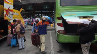 Penumpang memasukkan barang bawaan ke dalam bagasi bus di Terminal Kampung Rambutan, Jakarta, Sabtu (30/4/2022). [Suara.com/Angga Budhiyanto]