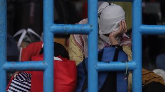 Calon penumpang tertidur saat menunggu kedatangan bus di Terminal Kampung Rambutan, Jakarta, Sabtu (30/4/2022). [Suara.com/Angga Budhiyanto]