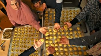 Wanita Palestina membuat kue tradisional Maamoul yang berisi kurma dan kacang-kacangan untuk persiapan hari raya Idul Fitri di kota Hebron, Palestina, Kamis (28/4/2022). [HAZEM BADER / AFP]