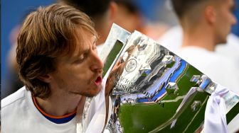 Gelandang Real Madrid Luka Modric mencium trofi Piala Liga Spanyol pada akhir pertandingan sepak bola Liga Spanyol antara Real Madrid dan Espanyol di Stadion Santiago Bernabeu, Madrid, Spanyol, Sabtu (30/4/2022). [Gabriel BOUYS / AFP]