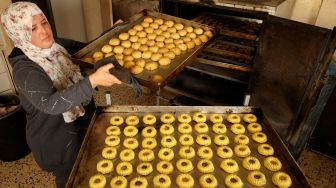 Wanita Palestina membuat kue tradisional Maamoul yang berisi kurma dan kacang-kacangan untuk persiapan hari raya Idul Fitri di kota Hebron, Palestina, Kamis (28/4/2022). [HAZEM BADER / AFP]