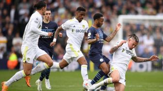 Gelandang Leeds United Kalvin Phillips (kanan) menjegal gelandang Manchester City Raheem Sterling (kedua dari kanan) saat pertandingan sepak bola Liga Premier Inggris antara Leeds United dan Manchester City di Stadion Elland Road, Leeds, Inggris, Sabtu (30/4/2022). [Oli SCARFF / AFP]