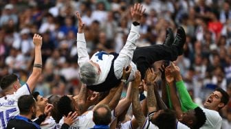 Para pemain Real Madrid menggendong mengangkat pelatih Carlo Ancelotti setelah menjadi juara Liga Spanyol pada akhir pertandingan sepak bola Liga Spanyol antara Real Madrid dan Espanyol di Stadion Santiago Bernabeu, Madrid, Spanyol, Sabtu (30/4/2022). [Gabriel BOUYS / AFP]