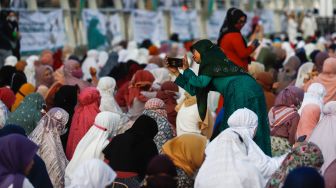 Seorang warga berswafoto sebelum menunaikan ibadah Shalat Idul Fitri 1 Syawal 1443 Hijriah di Jakarta International Stadium (JIS), Tanjung Priok, Jakarta Utara, Senin (2/5/2022). [Suara.com/Alfian Winanto]