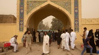 Warga muslim Irak mengunjungi makam kerabat mereka saat badai pasir pada hari pertama Idul Fitri di pemakaman Hassan al-Basri di Distrik Zubayr, Basra, Irak, Senin (2/5/2022). [Hussein Faleh / AFP]