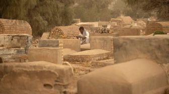 Warga muslim Irak mengunjungi makam kerabat mereka saat badai pasir pada hari pertama Idul Fitri di pemakaman Hassan al-Basri di Distrik Zubayr, Basra, Irak, Senin (2/5/2022). [Hussein Faleh / AFP]