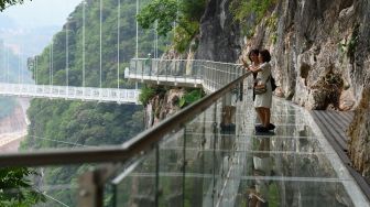 Pengunjung berdiri di pinggir jembatan kaca Bach Long di distrik Moc Chau, Son La, Vietnam, Jumat (29/4/2022). [Nhac NGUYEN / AFP]