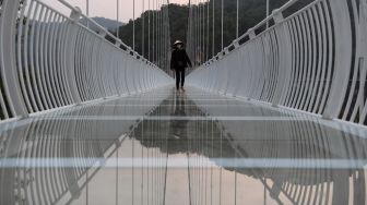 Pengunjung berjalan di jembatan kaca Bach Long di distrik Moc Chau, Son La, Vietnam, Jumat (29/4/2022). [Nhac NGUYEN / AFP]