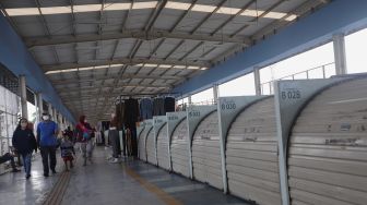 Warga berjalan melintasi deretan kios yang tutup di Skybridge Tanah Abang, Jakarta, Kamis (5/5/2022). [Suara.com/Angga Budhiyanto]