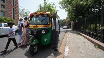 Pejalan kaki melewati Bajaj milik Mahender Kumar yang memiliki 'taman' di atapnya di New Delhi, India, Senin (2/5/2022). [Money SHARMA / AFP]