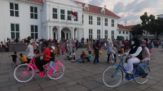 Warga menaiki sepeda saat berwisata di Taman Fatahillah, Kota Tua, Jakarta, Kamis (5/5/2022). [Suara.com/Angga Budhiyanto]