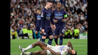 Reaksi gelandang Manchester City Phil Foden (Atas) ketika bek Real Madrid Eder Militao berbaring di lapangan saat pertandingan sepak bola leg kedua semifinal UEFA Liga Champions antara Real Madrid dan Manchester City di stadion Santiago Bernabeu, Madrid, Spanyol, Rabu (4/5/2022). [JAVIER SORIANO / AFP]