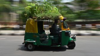 Pengemudi Bajaj Mahender Kumar mengendarai kendaraannya yang memiliki 'taman' di atapnya di New Delhi, India, Senin (2/5/2022). [Money SHARMA / AFP]
